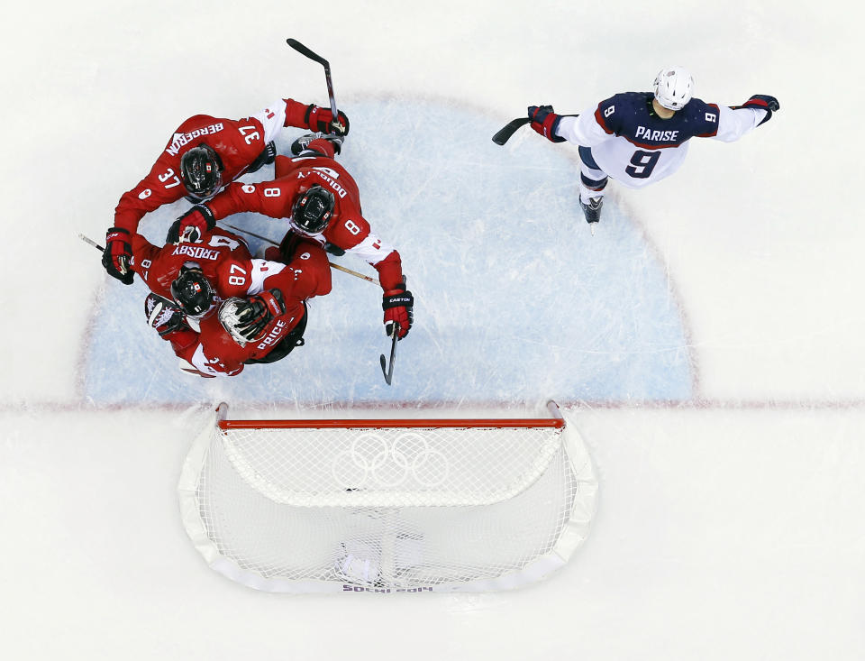 USA forward Zach Parise skates off the ice as Canadian players celebrate after a men's semifinal ice hockey game at the 2014 Winter Olympics, Friday, Feb. 21, 2014, in Sochi, Russia. Canada won 1-0 to advance to the gold medal game. (AP Photo/David J. Phillip)