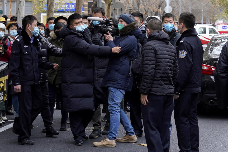 Foreign journalists are stopped by Chinese policemen as they try to film supporters of Zhou Xiaoxuan outside a courthouse in Beijing, Wednesday, Dec. 2, 2020. The Chinese woman who filed a sexual harassment lawsuit against a TV host told cheering supporters at a courthouse Wednesday she hopes her case encourages other "victims of gender violence" in a system that gives them few options to pursue complaints.(AP Photo/Andy Wong)