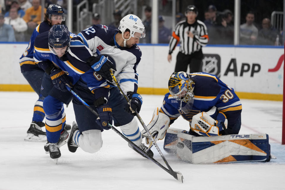 St. Louis Blues goaltender Joel Hofer (30) stops a push as Winnipeg Jets' Nino Niederreiter (62) watches and Blues' Marco Scandella (6) defends during the first period of an NHL hockey game Sunday, March 19, 2023, in St. Louis. (AP Photo/Jeff Roberson)