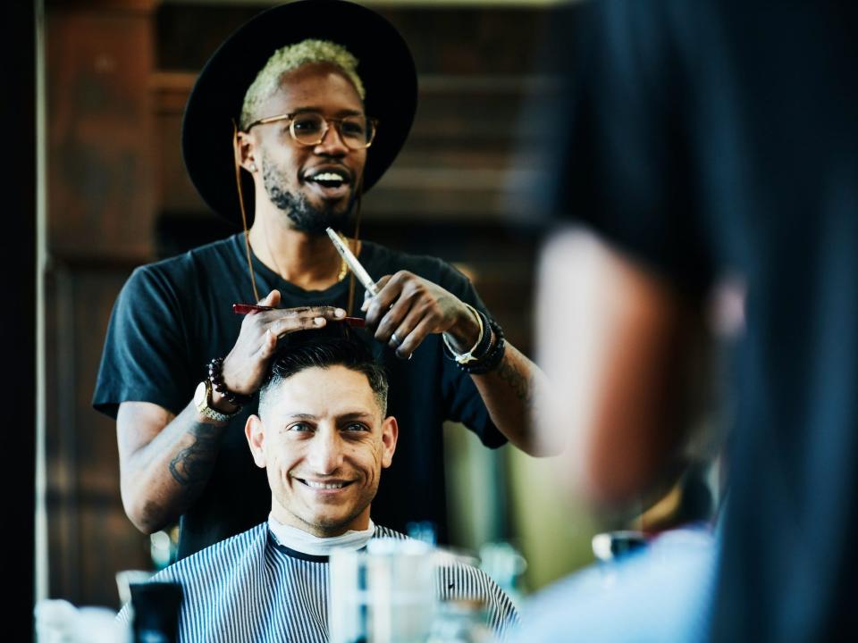 A barber talking to a client while cutting hair in a barber shop