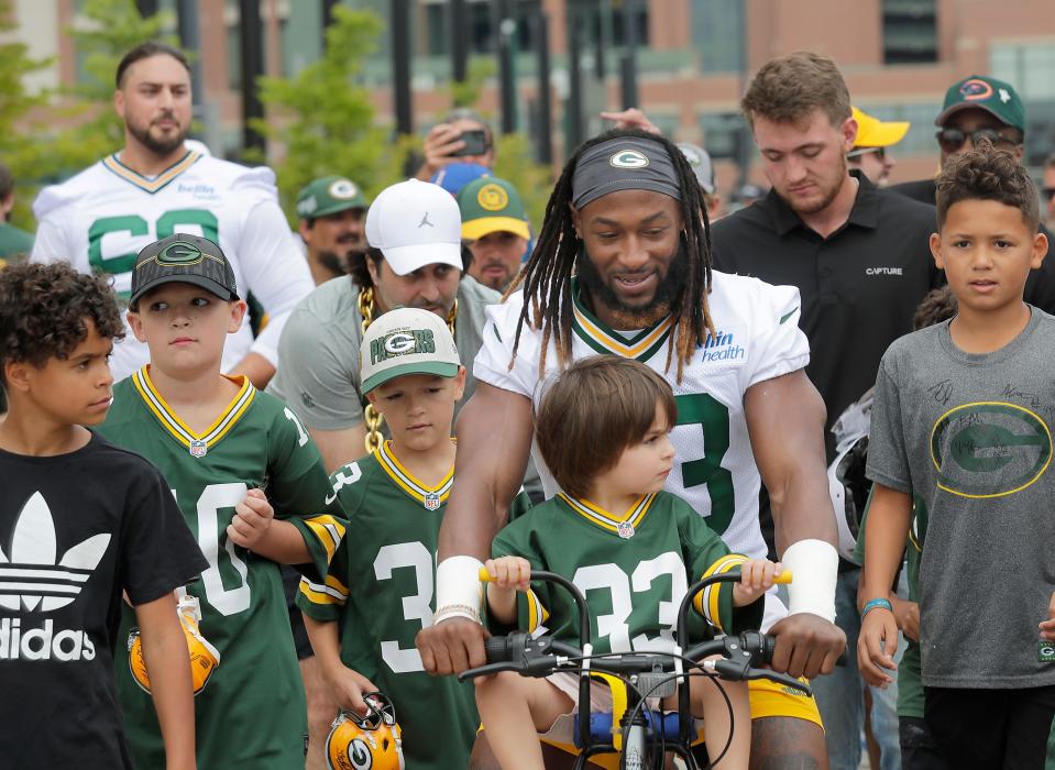 Green Bay Packers running back Aaron Jones (33) is surrounded by fans as he bikes with Knox Abboud, center, before the first day of training camp on Wednesday, July 26, 2023 at Ray Nitschke Field in Green Bay, Wis.