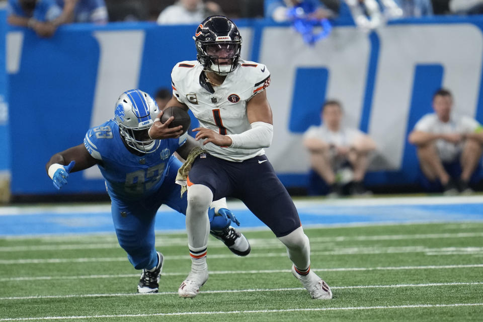 Chicago Bears quarterback Justin Fields (1) is chased by Detroit Lions defensive end Josh Paschal (93) during the second half of an NFL football game, Sunday, Nov. 19, 2023, in Detroit. (AP Photo/Paul Sancya)