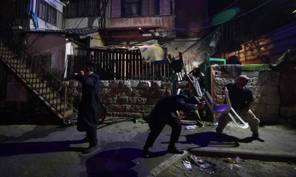 Israeli settlers take cover as projectiles are thrown at them in the Sheikh Jarrah neighbourhood of occupied east Jerusalem, on May 5.