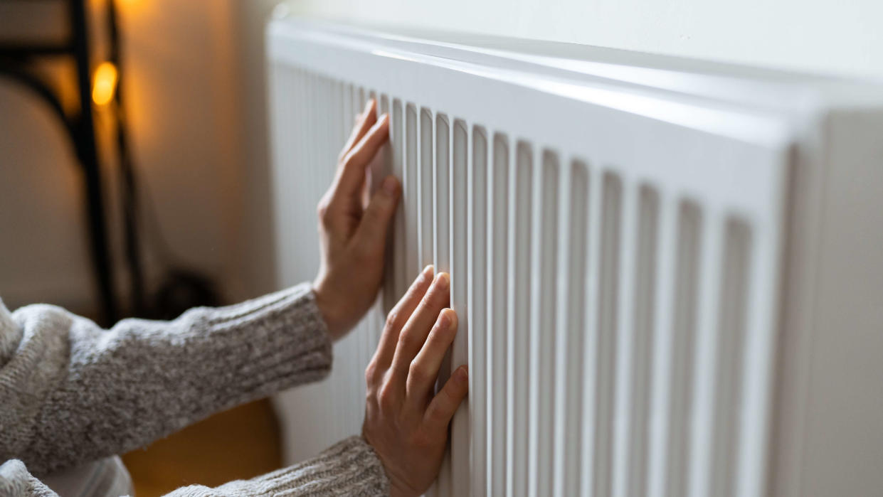  Woman placed both hands on a radiator to feel the heat. 