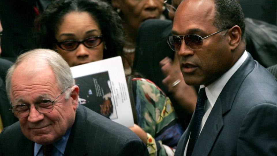 O.J. Simpson (right) and his trial lawyer, F. Lee Bailey (far left) find their seats at Johnnie L. Cochran’s Los Angeles funeral services in April 2005. (Photo by David McNew/Getty Images)