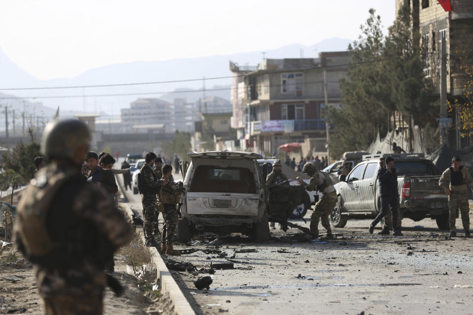Foreign and local security personnel gather at the site of car bomb attack in the Kabul, Afghanistan, Wednesday, Nov. 13, 2019. A car bomb detonated in the Afghan capital during Wednesday's morning commute, killing seven people and wounding at least seven, officials said. (AP Photo/Rahmat Gul)