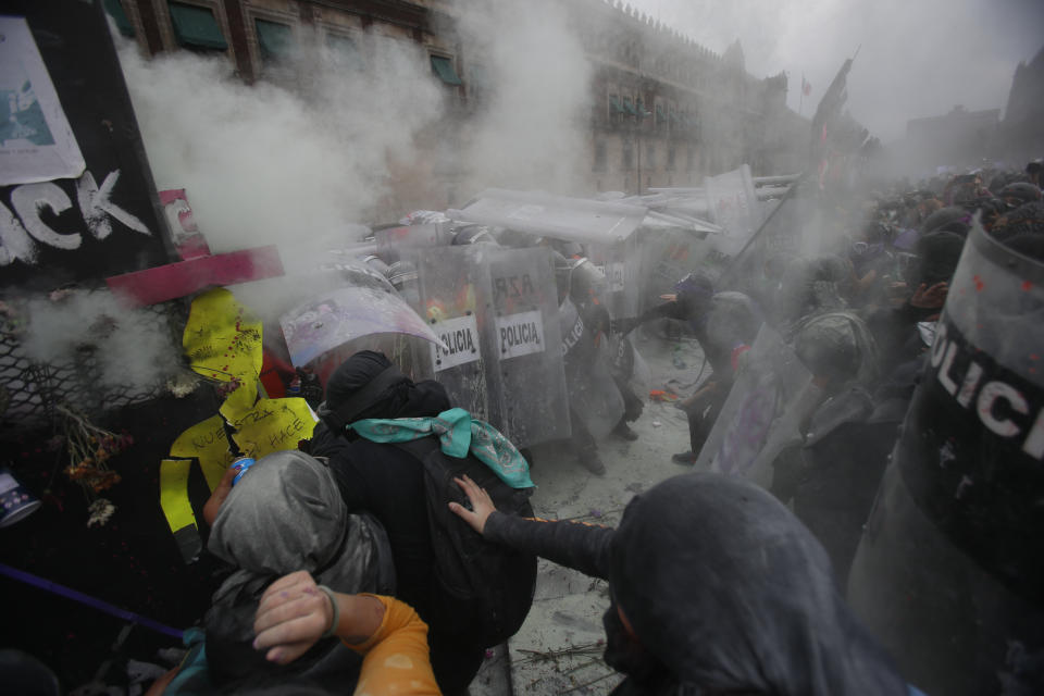 Demonstrators clash with the police at a breach on a barricade protecting the National Palace during a march to commemorate International Women's Day and protest against gender violence, in Mexico City, Monday, March 8, 2021. (AP Photo/Ginnette Riquelme)