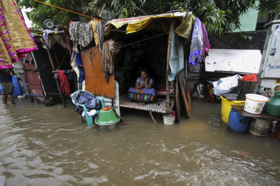 A woman sits inside her hut at a flooded street in Chennai, India, Wednesday, Nov.25, 2020. (AP Photo/R. Parthibhan)