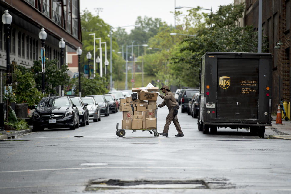 In this May 22, 2020, photo, a delivery man pushes a cart full of packages to deliver to an apartment building on an almost empty street in the Shaw neighborhood of Washington. As a candidate for the White House, President Donald Trump once said he wanted “whatever is best” for the residents of the nation’s capital. But over the course of his more than three years in office a disconnect between the president and District of Columbia has emerged -- a chasm that has only grown during the coronavirus pandemic. (AP Photo/Andrew Harnik)