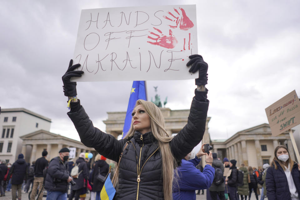 A banner reading "Hands off Ukraine" is held aloft during a demonstration against the war in Ukraine in front of the Brandenburg Gate in Berlin, Germany, Saturday, Feb. 26, 2022. (Joerg Carstensen/dpa via AP)