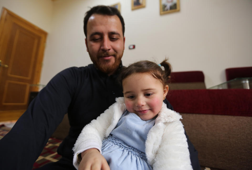 In this Sunday, Feb. 23, 2020 photo, Abdullah Mohammed plays with his daughter, three-year-old Salwa inside a house he recently fled to, near the Syrian-Turkish border, in Sarmada, Syria. Mohammed would do anything for his daughter, even if that means forcing himself to laugh with her at the sound of exploding bombs, to help her overcome her fear. Mohammed and Salwa became an overnight celebrity after a video they shot spread on social media, widely shared as a reminder of the horrors faced by children in Syria. (AP Photo/Ghaith Alsayed)