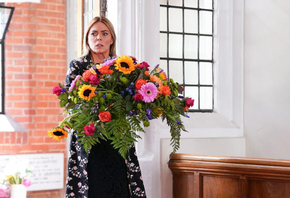 eastenders patsy kensit as emma harding at lola's funeral with a large bouquet of flowers