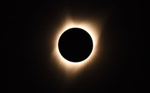 The sun's corona is visible as the moon passes in front of the sun - Credit: AFP