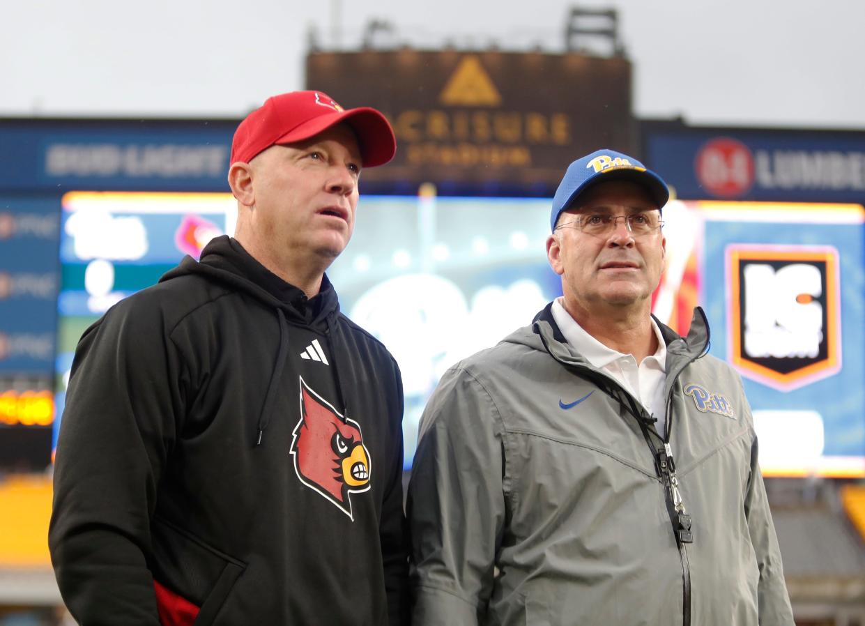 Oct 14, 2023; Pittsburgh, Pennsylvania, USA; Louisville Cardinals head coach Jeff Brohm (left) and Pittsburgh Panthers head coach Pat Narduzzi (right) talk at mid-field before their teams play at Acrisure Stadium. Mandatory Credit: Charles LeClaire-USA TODAY Sports