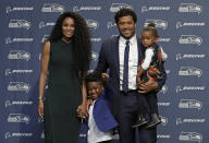 FILE - In this April 17, 2019, file photo, Seattle Seahawks NFL football quarterback Russell Wilson poses for photos with his wife, Ciara; their daughter, Sienna; and Ciara's son, Future, in Renton, Wash. The couple are putting their money and celebrity behind rebranding a charter school, which advocates hope will boost the troubled Washington state charter school sector that has suffered from enrollment problems after years of legal challenges. (AP Photo/Ted S. Warren, File)