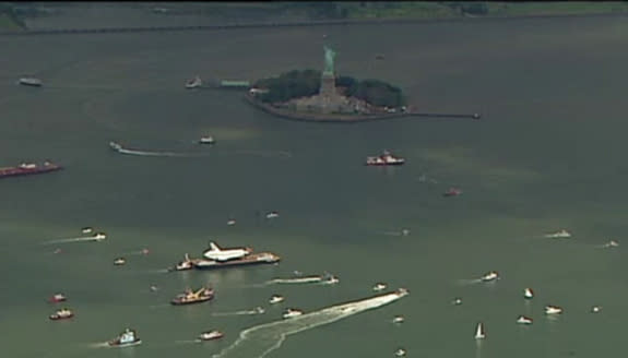 This still from an NBC New York webcast shows NASA's space shuttle Enterprise passing the Statue of Liberty while sailing up the Hudson River to the Intrepid Sea, Air and Space Museum on June 6, 2012.