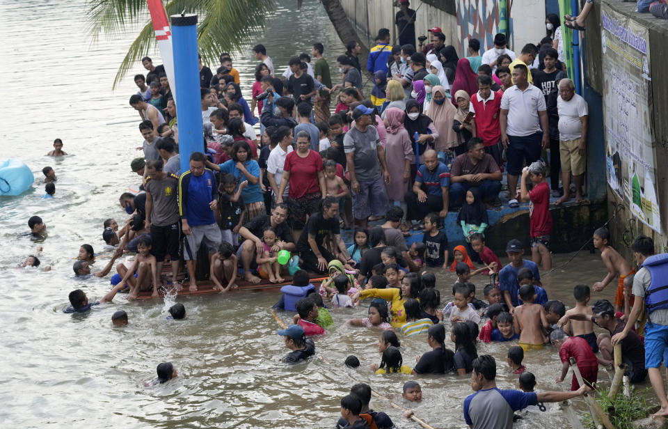 People bathe in the Cisadane River on the first evening of the holy fasting month of Ramadan in Tangerang, Indonesia, Saturday, April 2, 2022. Muslims followed local tradition to wash in the river to symbolically cleanse their soul prior to entering the holiest month in Islamic calendar. (AP Photo/Tatan Syuflana)