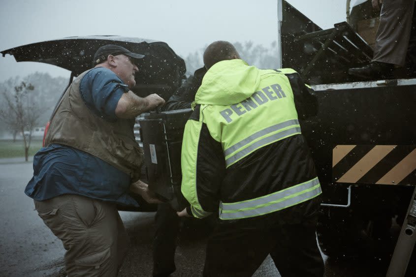 José Andrés (L) helps Pender County, NC police officers lift large food container onto truck - Credit: National Geographic