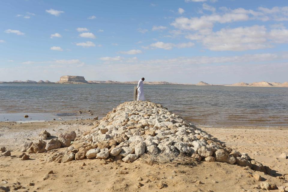 A man stands on a small bridge over the salt lake at a farm near the Salinas of Siwa