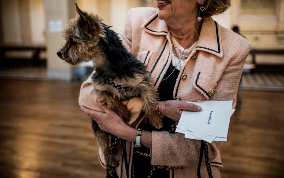 A woman carries her dog as she cast her vote at a polling booth in Lyon - Credit: JEFF PACHOUD/AFP