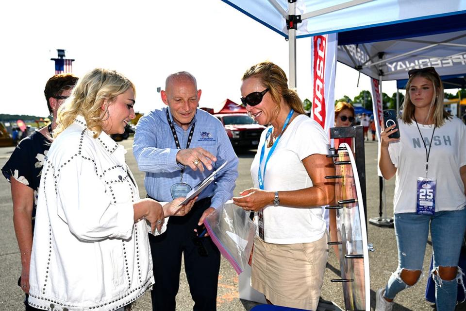 MTSU alumna Hunter Wolkonowski, left, of Winchester, Tenn., better known as HunterGirl from her runner-up finish in the last American Idol competition, receives a photograph of her with the late country music icon Charlie Daniels from retired Army Lt. Gen. Keith Huber, center, and Daniels Center Director Hilary Miller. It took place at the Rackley Roofing 200 NASCAR Camping World Truck Series event at the Nashville Superspeedway in Gladeville, Tenn.