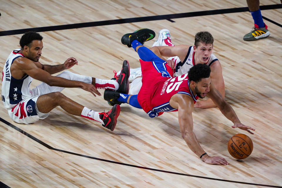 Philadelphia 76ers guard Ben Simmons (25) goes for a loose ball with Washington Wizards guard Jerome Robinson, left, and forward Moritz Wagner, right. during the first half of an NBA basketball game Wednesday, Aug. 5, 2020 in Lake Buena Vista, Fla. (AP Photo/Ashley Landis)