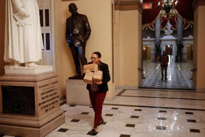 A staff member carries boxes of hand sanitizer towards the House Chamber floor before a vote on relief for the coronavirus (COVID-19) disease on Capitol Hill in Washington