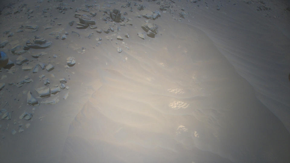 a photo looking down at a sandy patch of martian ground, with boulders strewn near the top of the frame.