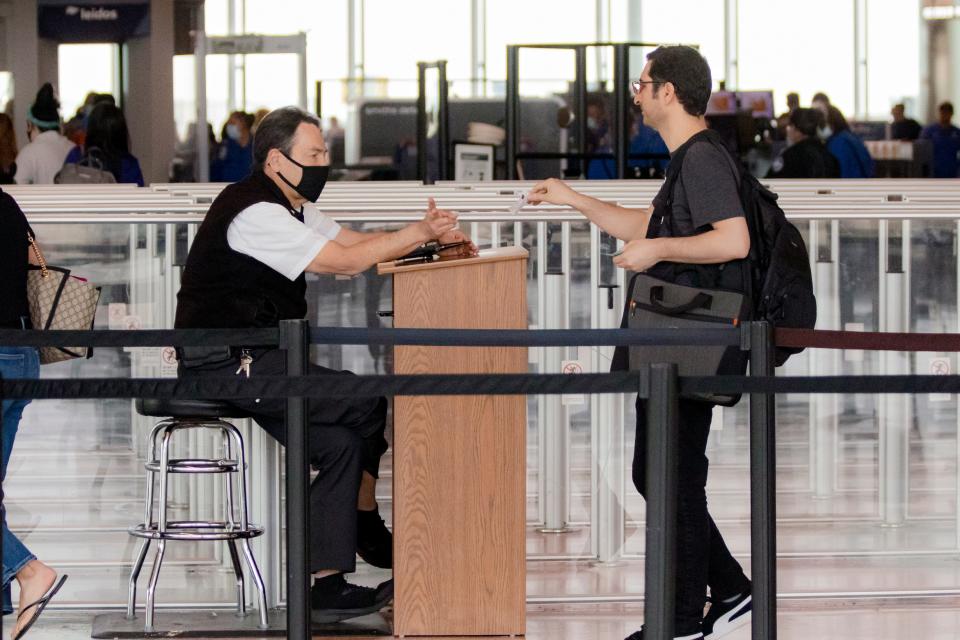 A maskless traveler makes his way through Will Rogers World Airport past an employee still opting for a mask on Wednesday. Masks are now optional for employees and passengers at the airport following a Monday ruling by a Florida judge.