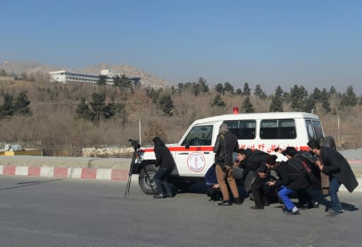 In this photo by slain AFP photographer Shah Marai, Afghan journalists take cover behind an ambulance near the Intercontinental Hotel during a fight between gunmen and security forces in Kabul on January 21, 2018