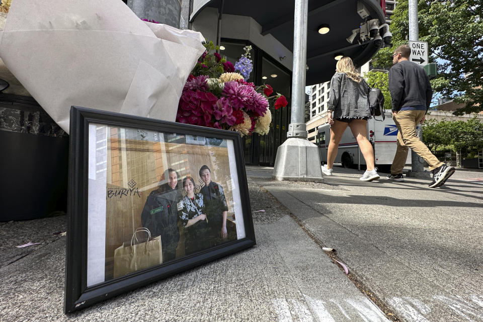 A picture shows Eina Kwon, center, and her husband Sung Kwon, right, at a memorial in Seattle, Friday, June 16, 2023. A pregnant woman who was killed in what appears to have been a random shooting in downtown Seattle this week has been identified as Eina Kwon, the owner of a sushi restaurant near the city's famed Pike Place Market. Her husband survived the attack. (AP Photo/Manuel Valdes)