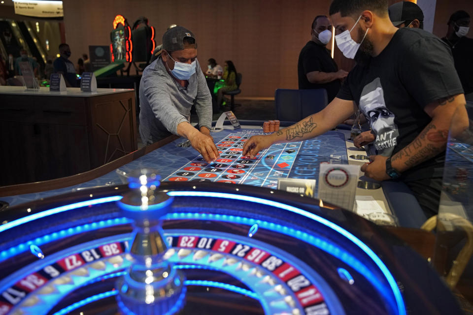 FILE - In this July 4, 2020, file photo, people wear face masks as a precaution against the coronavirus as they play roulette on the Fourth of July at the Strat hotel-casino in Las Vegas. With the ongoing coronavirus pandemic curtailing tourism, visitors have found quiet gambling floors, shuttered showrooms and inexpensive rates. Some Las Vegas Strip casinos have been allowed to open at 100% capacity, officials said Tuesday, May 4, after showing Nevada state regulators that at least 80% of their employees have received at least one shot of coronavirus vaccine. (AP Photo/John Locher, File)