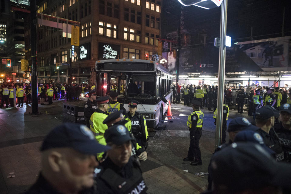 Police block fans from gathering on a bus that was damaged during street celebrations after the Toronto Raptors defeated the Golden State Warriors during Game 6 NBA Finals to win the NBA Championship, in Toronto on Friday, June 14, 2019. (Tijana Martin/The Canadian Press via AP)