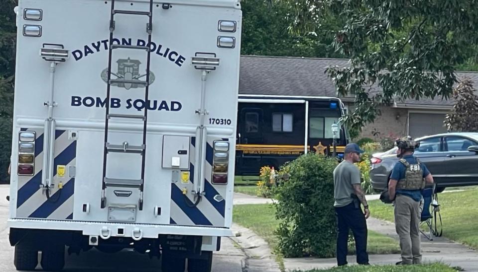 Dayton Police Bomb Squad members and an person wearing FBI gear stand near the scene of a large investigation after four people were shot and killed in Butler Twp. (WHIO Staff)