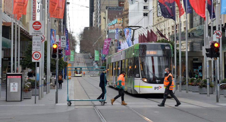 Three men walk across a CBD street.