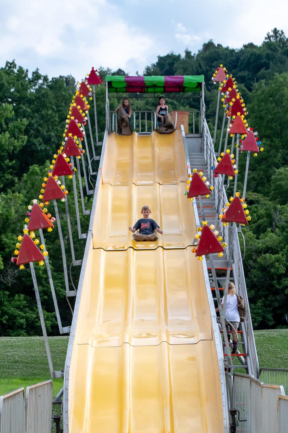 Kids take turns sliding down an enormous slide set up with the carnival rides at the Ohio Hills Folk Festival in Quaker City. The four-day event highlighted local artisans, hosts a car show, and multiple parades.