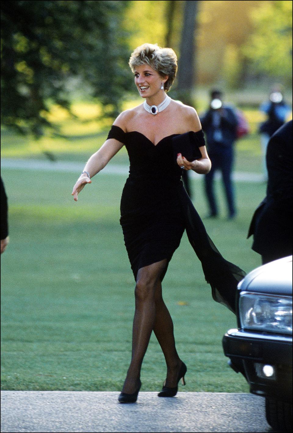 Princess Diana wears the "revenge dress" and stretches her hand out to greet someone