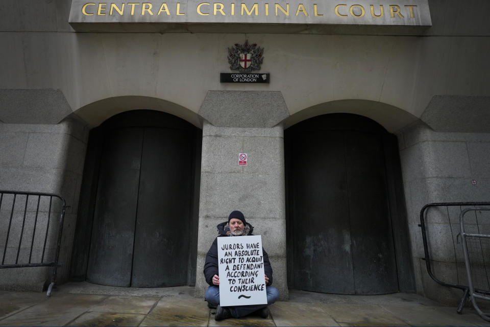 A demonstrator holds a banner outside The Old Bailey, the Central Criminal Court of England and Wales, in London, Monday, Dec. 4, 2023. Britain is one of the world's oldest democracies, but some worry that essential rights and freedoms are under threat. They point to restrictions on protest imposed by the Conservative government that have seen environmental activists jailed for peaceful but disruptive actions. (AP Photo/Kirsty Wigglesworth)