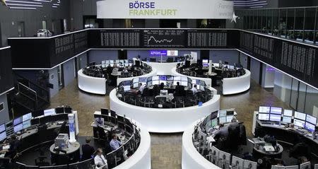 Traders work at their desks in front of the German share price index, DAX board, at the stock exchange in Frankfurt, Germany, November 30, 2016. REUTERS/Staff/Remote