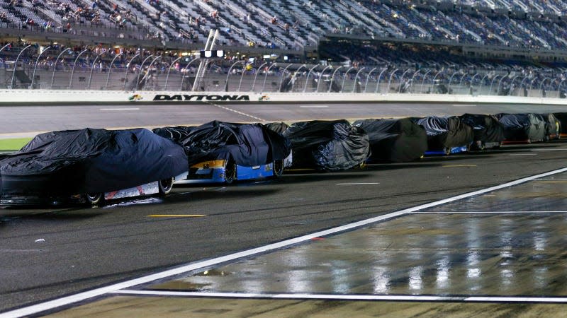 A photo of race cars covered to protect them from the rain.