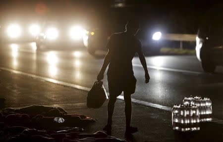 A migrants walks past bottled water as he waits for buses bound for Austria and Germany, along the M1 highway near Budapest, Hungary, September 5, 2015. REUTERS/David W Cerny