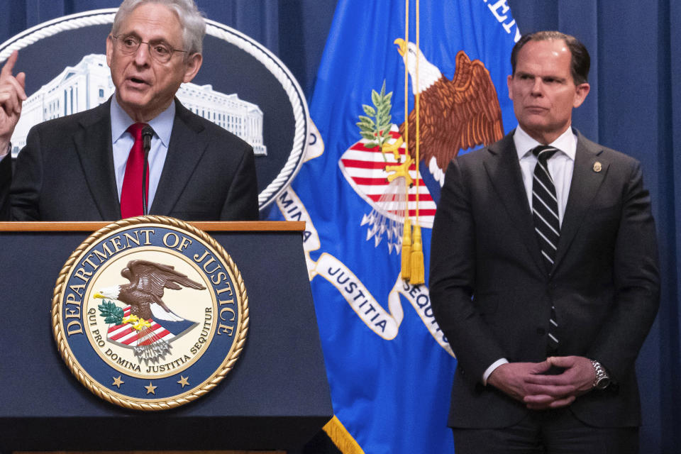 FILE - DEA Deputy Administrator Louis Milione, right, stands behind Attorney General Merrick Garland during the announcement of an international law enforcement operation targeting fentanyl and opioid traffickers on the Darknet during a news conference at the Department of Justice, Tuesday, May 2, 2023, in Washington. Milione, the DEA’s second-in-command, quietly resigned in 2023, amid reporting by The Associated Press that he previously consulted for a pharmaceutical distributor sanctioned for a deluge of suspicious painkiller shipments and did similar work for the drugmaker that became the face of the opioid epidemic: Purdue Pharma. (AP Photo/Nathan Howard, File)