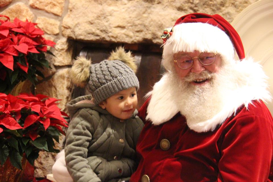 Norma Escobar, 3, visits with Santa Claus at the Hotel Pattee on Friday, Nov. 25 after the 2022 Lighted Holiday Parade in Perry.