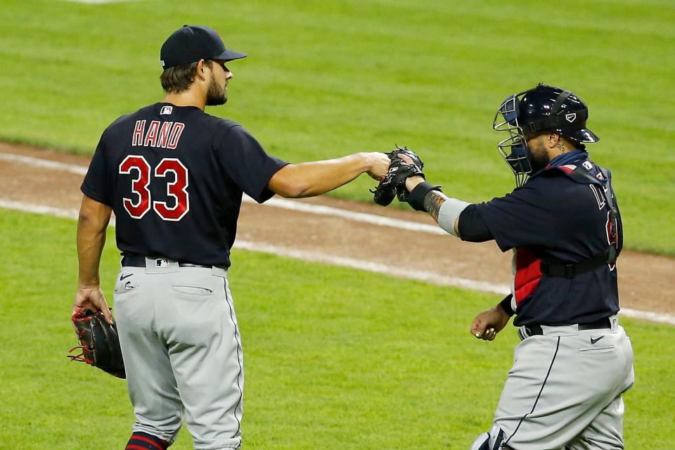 Cleveland Indians relief pitcher Brad Hand (33) and catcher Sandy Leon (9) celebrate after the final out of the ninth inning of the MLB interleague game between the Cincinnati Reds and the Cleveland Indians at Great American Ball Park in downtown Cincinnati on Tuesday, Aug. 4, 2020. The Indians made a comeback, scoring two runs in both the seventh and eighth innings to win 4-2.