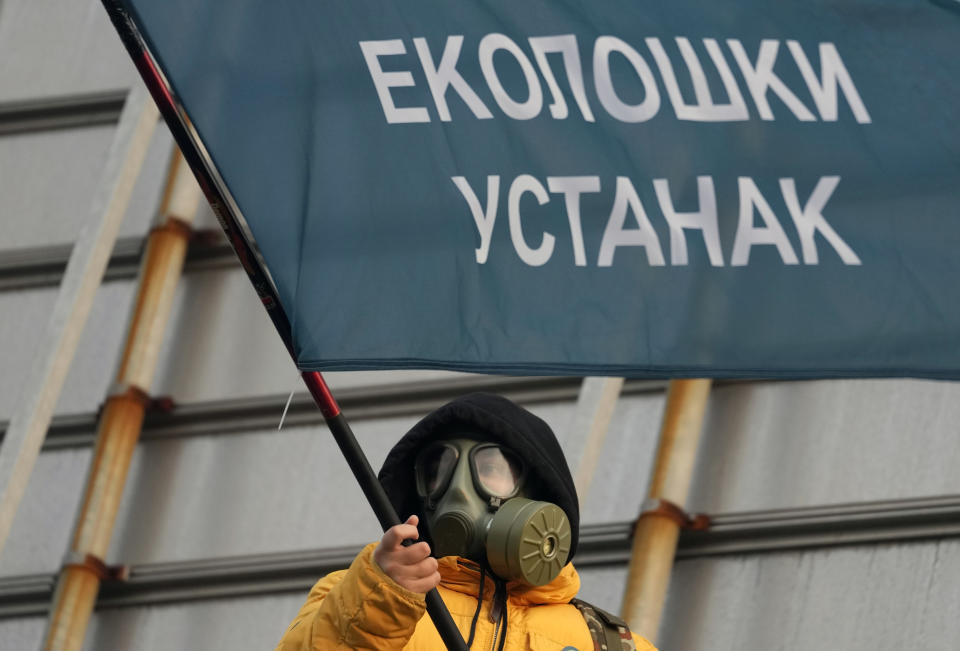 A protester wearing a face mask waves a flag on the highway during a protest in Belgrade, Serbia, Saturday, Dec. 4, 2021. Thousands of protesters have gathered in Belgrade and other Serbian towns and villages to block roads and bridges despite police warnings and an intimidation campaign launched by authorities against the participants. (AP Photo/Darko Vojinovic)