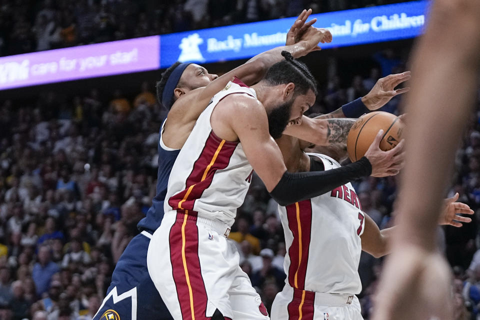 Miami Heat forward Caleb Martin, center, rebounds the ball after Denver Nuggets guard Jamal Murray misses a game-tying 3-point shot during the fourth quarter of Game 2 of basketball's NBA Finals, Sunday, June 4, 2023, in Denver. (AP Photo/Mark J. Terrill)