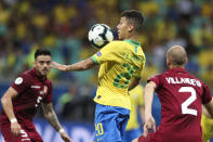 Brazil's Roberto Firmino, center, controls the ball between Venezuela's Mikel Villanueva, right, and Venezuela's Junior Moreno, right, during a Copa America Group A soccer match at the Arena Fonte Nova in Salvador, Brazil, Tuesday, June 18, 2019. (AP Photo/Natacha Pisarenko)