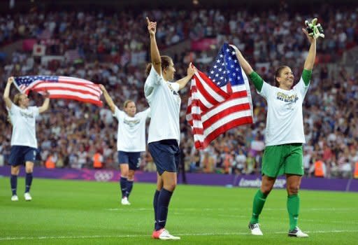 La golera estadounidense Hope Solo (D) festeja con compañeras exhibiendo la bandera de su país tras ganar a Japón en la final del fútbol femenino de los Juegos de Londres 2012, el 9 de Agosto de 2012 en el estadio de Wembley, en Londres. EEUU ganó 2-1 y salió campeón olímpico por cuarta vez en la categoría. (AFP | luis acosta)