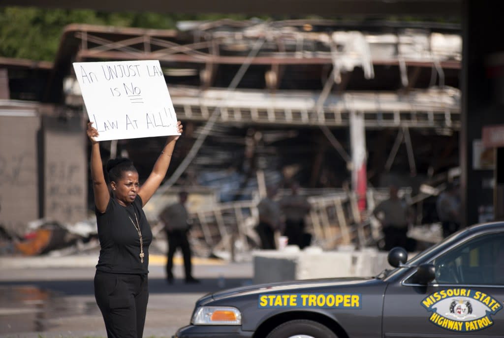 Protesters appeal to motorists for support while rallying on Monday, Aug. 11, 2014 in front of the QT gas station in Ferguson, Mo., that was looted and burned during rioting overnight that followed a candlelight vigil honoring 18-year-old Michael Brown, who was shot Aug. 9, 2014 by Ferguson police officers. (AP Photo/Sid Hastings, File)