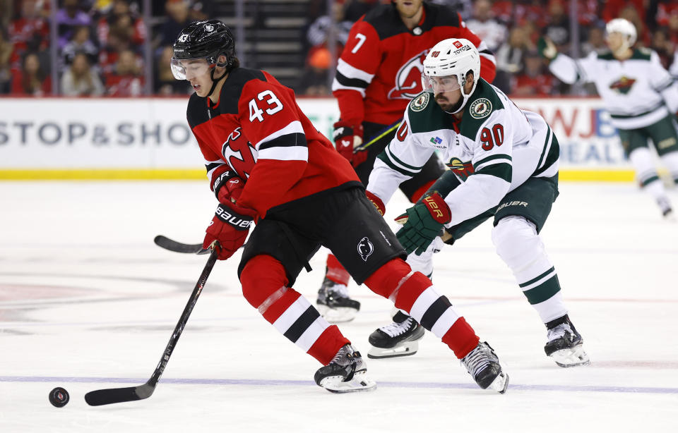 New Jersey Devils defenseman Luke Hughes (43) controls the puck against Minnesota Wild left wing Marcus Johansson (90) during the first period of an NHL hockey game, Sunday, Oct. 29, 2023, in Newark, N.J. (AP Photo/Noah K. Murray)